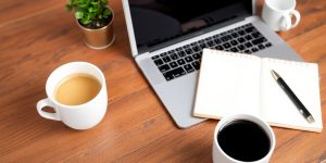 A workspace with laptop and coffee cup for content creation.